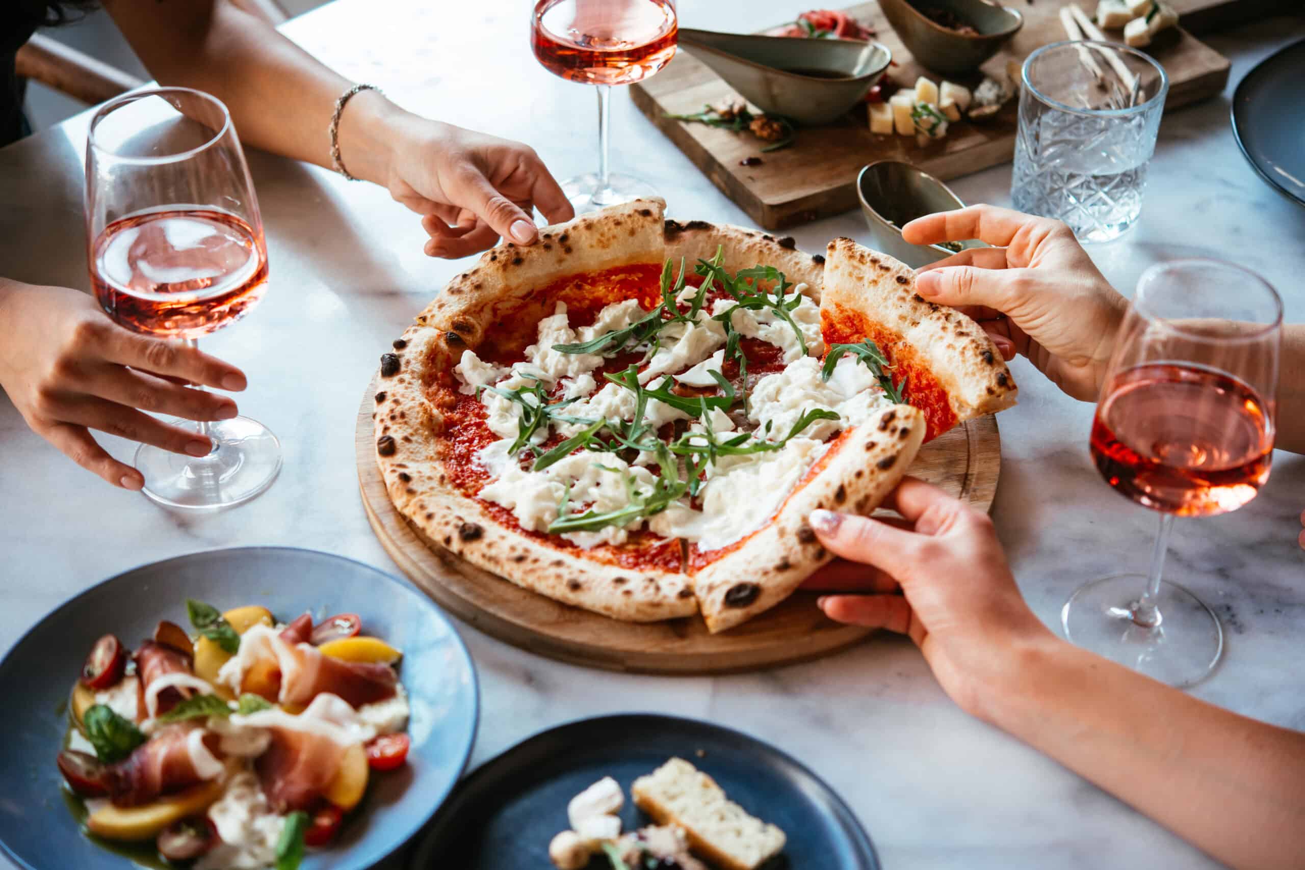 People sharing pizza and drinks.
